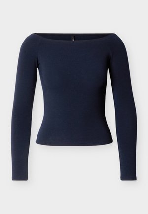 Tumesinise värvusega pikkade varrukatega ülaosa, mis on keha järgi lõigatud ja millel on õlgadest paljastav dekoltee. Pehme, sile kangas ja ümaralt lõigatud alumine serv. Ilma nähtavate detailideta.