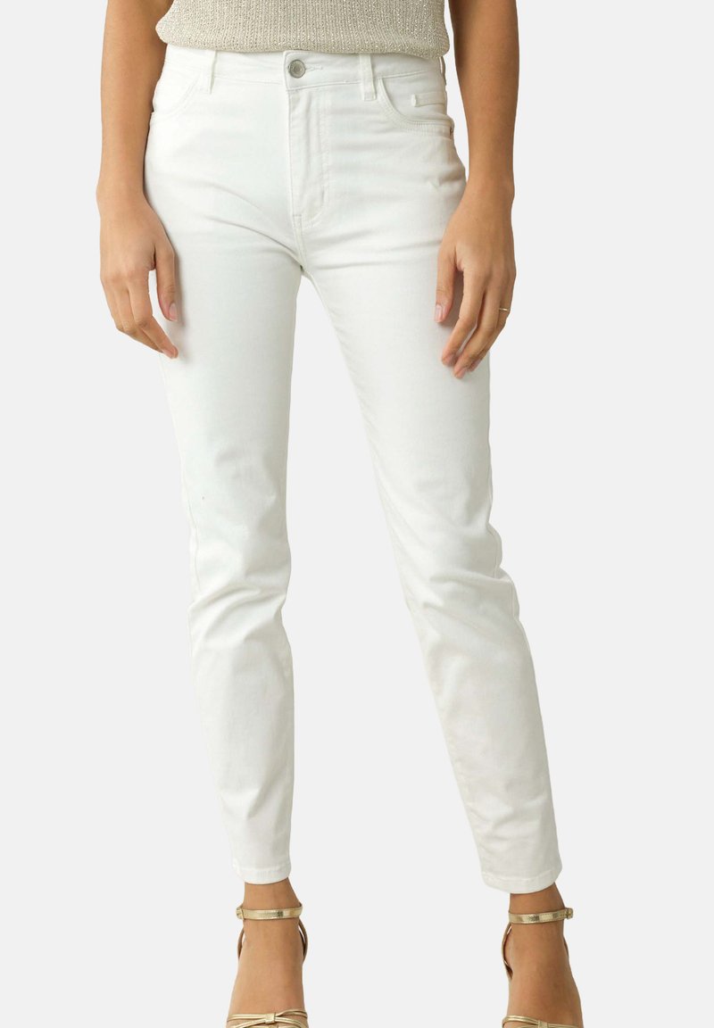 Jean skinny en denim blanc avec une taille haute, un design à cinq poches et des détails de couture subtils. Texture lisse avec une silhouette ajustée.