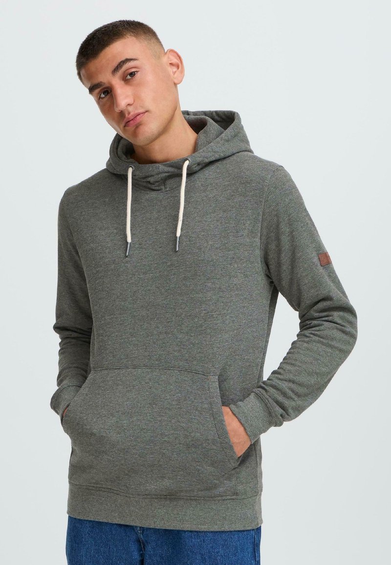 Sweat-shirt gris en matériau doux avec une capuche à cordon, une poche frontale et des poignets côtelés. Il présente un petit logo brodé sur la manche.