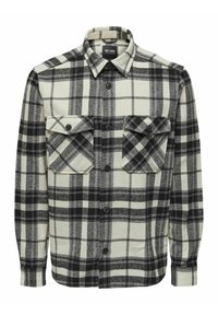Camisa de franela a cuadros en blanco y negro con cierre de botones, dos bolsillos en el pecho, cuello puntiagudo y mangas largas. Tela texturizada.