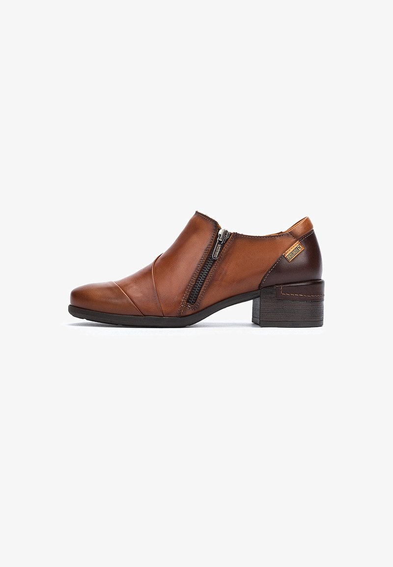 Bottines en cuir marron avec un faible talon bloc, fermeture éclair sur le côté, coutures courbées et texture lisse. Comprend un accent de talon plus foncé en contraste.