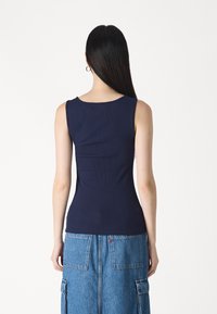 Tricou fără mâneci, de culoare bleumarin, cu un decolteu rotund, siluetă ajustată și textură netedă. Fără detalii sau embellishments proeminente.