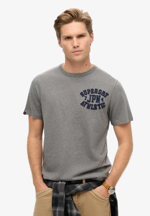 Grå bomulds t-shirt med "Superdry JPN Athletic" i marineblå broderi, klassisk rund hals og korte ærmer. Casual pasform med synlige sømme.