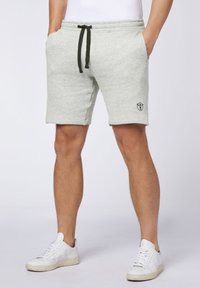 Light gray cotton shorts with an elastic waistband, black drawstring, side pockets, and a small black logo embroidered on the thigh.