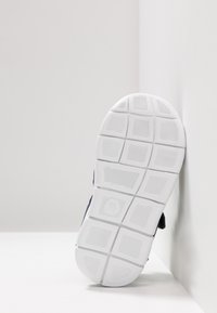 Sport sandal with a white rubber sole featuring a textured grip pattern, navy upper material, and adjustable straps.