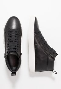 Czarne skórzane wysokie trampki o gładkim wykończeniu, z czarnymi sznurowadłami, bocznymi zamkami błyskawicznymi i białą gumową podeszwą.