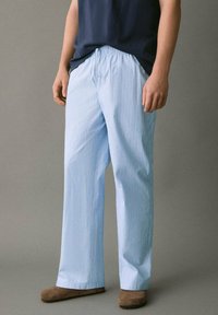 Vaaleansinisen raidalliset aamutakit, joissa on elastinen vyötärö ja naru; suorat lahkeet; pehmeä kankaan rakenne; käytetään ruskeiden tohveleiden kanssa.