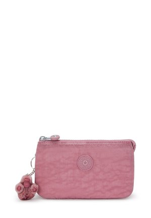 Rosa rechteckige Stofftasche mit Reißverschluss, an der ein kleiner flauschiger Affen-Schlüsselanhänger befestigt ist, sowie einem runden Logo-Patch auf der Vorderseite.