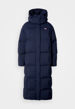 Tamsiai mėlynas ilgas pūkinis paltas su gobtuvu, su įsiūtu piešiniu, aukštu apykakle ir šoninėmis užtrauktukų kišenėmis. Minkštas, paminkštintas audinys.