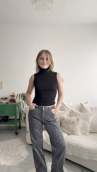 Svart turtleneck-overdel i imitert skinn, figursydd design; grå bukser med leopardmønster; myk stofftekstur; rette bein; synlige frontlommer.