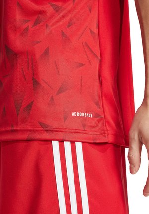 Maglia sportiva rossa con un motivo triangolare testurizzato, dettagli bianchi e marchio Adidas AEROREADY vicino all'orlo.