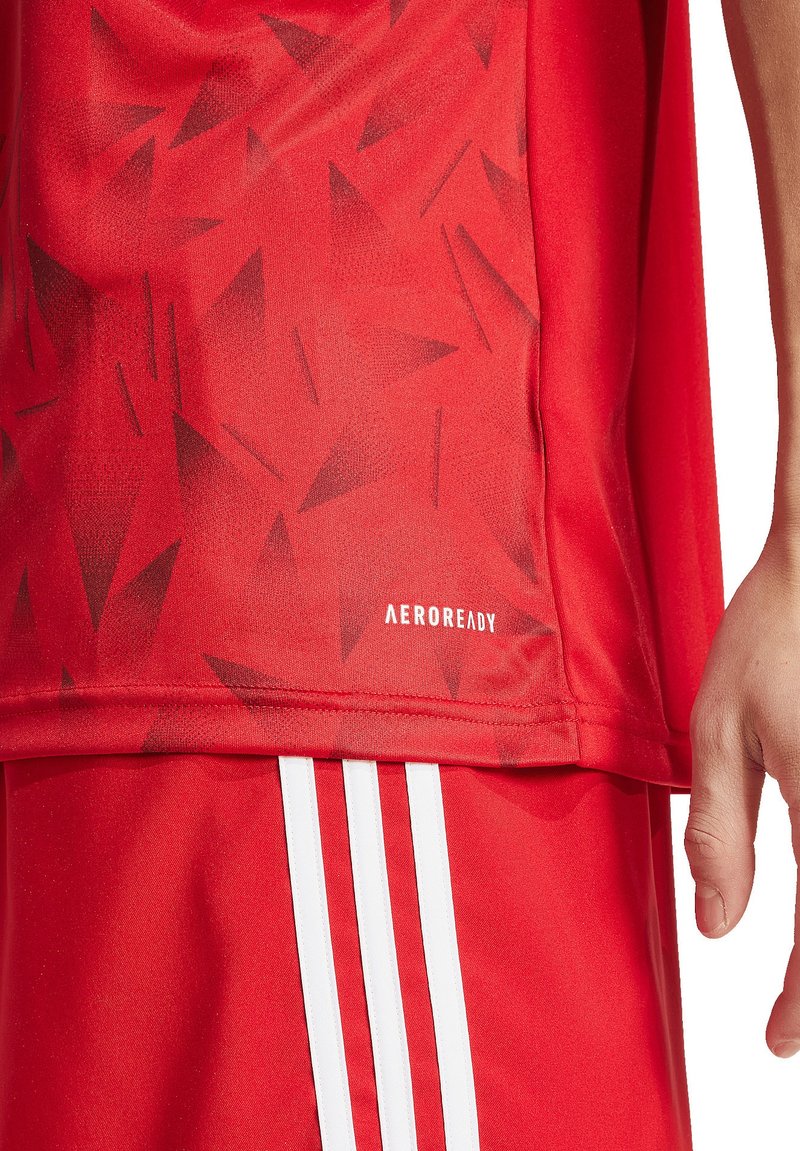 Maglia sportiva rossa con un motivo triangolare testurizzato, dettagli bianchi e marchio Adidas AEROREADY vicino all'orlo.