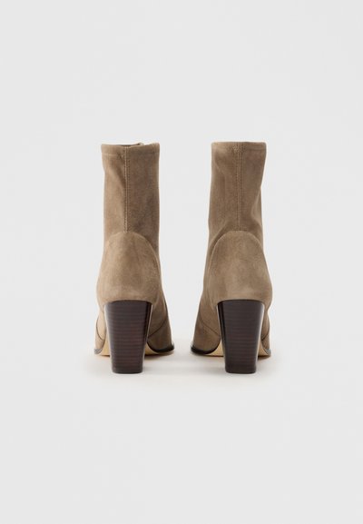 Tan suede ankle boots with a smooth finish, rounded toe, and a mid-height wooden heel. Back-zip closure and seam detailing are visible.