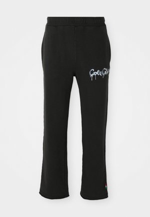 Svart joggebukser med elastisk liv, sidelommer, hvit og blå "Gaola Gaola" tekst på høyre lår, og liten rød, hvit og grønn etikett på venstre ankel.