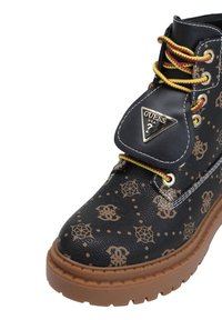 Stivaletto alla caviglia nero con lacci, in pelle stampata, con accenti marroni e suola in gomma nervata. Presenta una placca con logo dorato e lacci gialli.