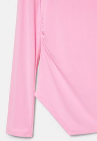 Haină roz cu mâneci lungi, cusătură laterală adunată și detaliu asimetric la tiv, pe fundal alb.