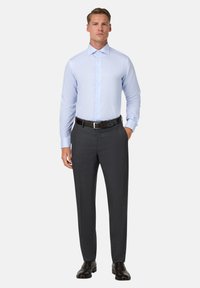 Gai zils svītrainais krekls ar izplestu apkakli, savienots ar tumši pelēkiem piegrieztiem biksēm un melniem ādas apaviem.