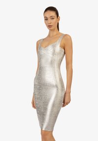Srebrna sukienka bodycon z teksturowanej tkaniny, dekoltem w serek, grubymi ramiączkami i długością do kolan. Charakteryzuje się dopasowanym krojem i subtelnym połyskiem.