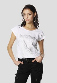 T-shirt en coton blanc avec un motif léopard argenté et des accents en dentelle. Associé à un pantalon noir avec des poches latérales.