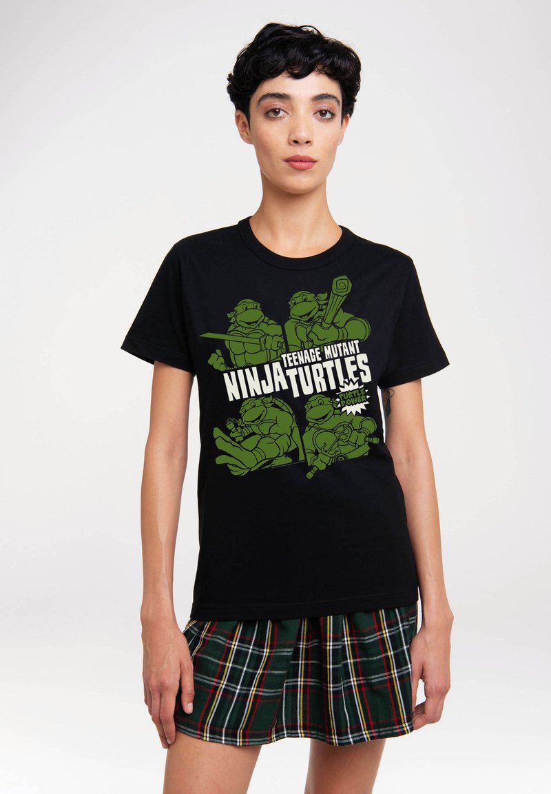 Black cotton t-shirt featuring green Teenage Mutant Ninja Turtles graphics. The design includes characters with weapons and the text "Ninja Turtles."
