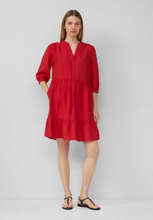 Rotes Kleid mit V-Ausschnitt, dreiviertellangen Puffärmeln, gestuftem Rüschensaum und seitlichen Taschen. Hergestellt aus leichten Stoffen mit einer weichen Textur.