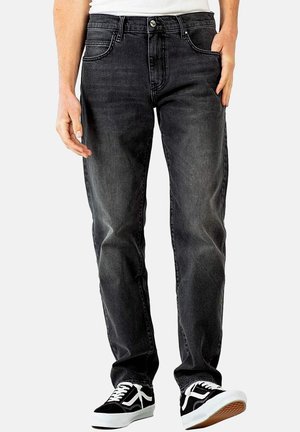 Schwarze Jeans aus Denim mit geradem Schnitt, fünf Taschen und Kontrastnähten. Getragen mit schwarz-weißen Sneakers.