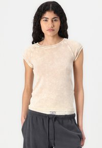 Light beige fitted t-shirt made of soft fabric. Features short sleeves and a rounded neckline, with a slightly textured surface.