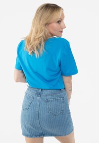 Turquoise cotton t-shirt paired with a light blue striped denim skirt. The outfit features short sleeves and a fitted design.