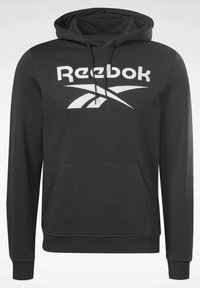 Sudadera negra de tela, con un bolsillo frontal, puños acanalados y un logo blanco de Reebok en el pecho con un diseño en contraste.
