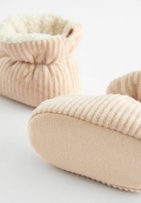 Rosa ribbat tygtofflor med mjukt, lurvigt foder. Rund tå och elastisk manschettdesign för värme och komfort.