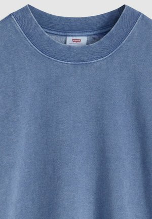 Blauwe crewneck trui van zacht katoen, met een geribde halslijn en een subtiele textuur. Voorzien van een klein merklabel bij de kraag.