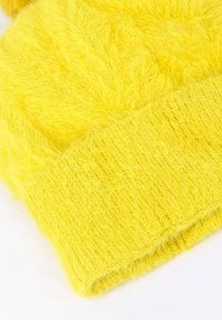 Tessuto giallo soffice con una consistenza morbida e polsini a costine. Presenta un colore vivace e un aspetto piumoso, ideale per il calore.