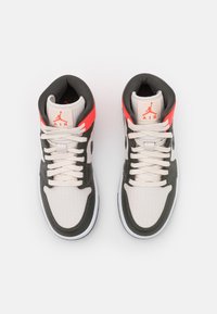 Paire de baskets montantes blanches, noires et rouges avec des lacets blancs et le logo Jumpman Air rouge sur les languettes rembourrées, vues de dessus.