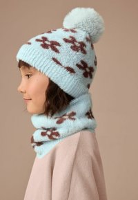 Gorro de punto azul claro y bufanda a juego con un pompón esponjoso, con patrones florales marrones y un acabado suave y texturizado.