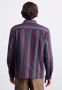 Multicolored button-up shirt featuring a patterned design with vertical stripes in purple, blue, and green, and long sleeves with button cuffs.