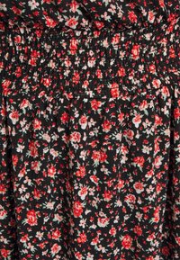 Svart tyg med ett litet blommönster i rött och vitt. Materialet har en rynkad textur vid midjan för en figurnära design.