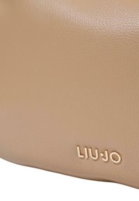 Borsa in pelle beige con una texture liscia, forma arrotondata e logo "LIU JO" in oro embossato.