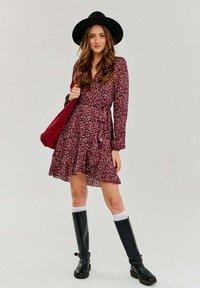 Bordový kvetinový šaty s dlhými rukávmi a volánovým lemom. Nosené s čiernymi vysokými čižmami a zodpovedajúcou čiapkou, drží bordovú tašku.