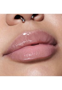 Glanzende lichtroze lippen met een gladde textuur; voorzien van een zilveren septumpiercing en een natuurlijke huidtint als achtergrond.