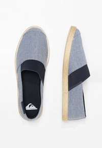 Slip-on skor med en överdel i blå denim, med ett marinblått elastiskt band, beige gummisula och en logodetalj på insidan.