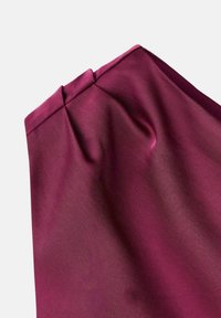 Bordová tkanina s jemnou, hladkou textúrou a jemnými záhybmi na vrchu, vytvárajúcimi drapériu a štruktúrovaný tvar.