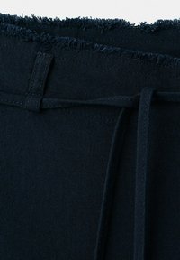 Dunkel marineblauer, strukturierter Stoffbund mit ausgefranstem Rand und einem durch eine Gürtelschlaufe gefädelten Kordelzug.