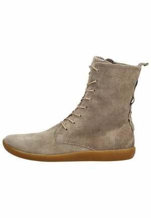 Stivaletto alla caviglia in suede marrone chiaro con lacci sottili, suola piatta in gomma e cerniera laterale su sfondo bianco.
