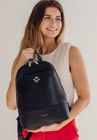 Schwarzer Leder-Rucksack mit elegantem Design, silbernen Beschlägen, Oberreißverschluss und geprägtem Logo. Verstellbare Riemen für zusätzlichen Komfort.