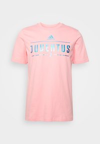 Růžové bavlněné tričko s kulatým výstřihem, krátkými rukávy a nápisem "JUVENTUS" vytištěným odrazivými modrými a stříbrnými písmeny s logem Adidas nad ním.