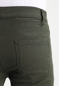 Olijfgroene stretch denim jeans met een zachte textuur, aansluitend ontwerp en twee achterzakken met naaddetails.