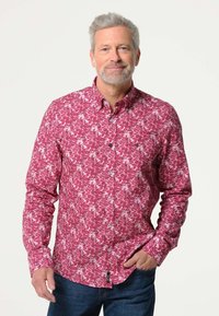 Rode bloemenpatroon button-down overhemd met lange mouwen, voorzien van witte knopen en een gebogen zoom. Gepaard met donkerblauwe jeans.