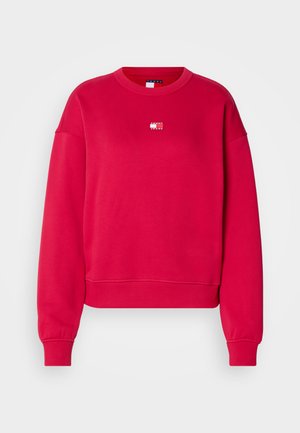 Crvena majica s dugim rukavima i okruglim izrezom, rebrasti manžeti i malim bijelim logotipom na prsima. Izrađena od mekanog, strukturiranog materijala.