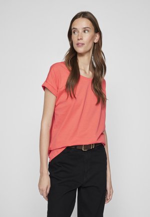 Coral short-sleeve t-shirt with rolled cuffs, relaxed fit, made of soft fabric, paired with black high-waisted trousers and a brown belt.
