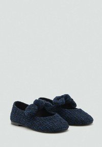 Pantofole intrecciate blu e nere con un accento annodato sulla parte anteriore, suola piatta e punta rotonda. Tessuto morbido e testurizzato, design a basso profilo.